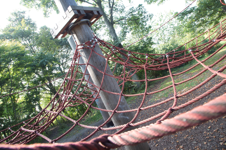 Close up photo of a roped net joined to a wooden post that children play and climb on.
