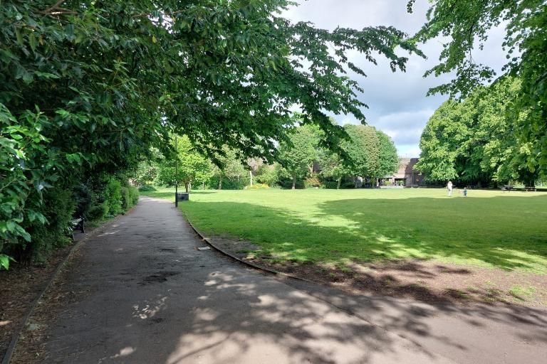 A path and large grassy space surrounded by trees on a sunny day at Gosforth Central Park.