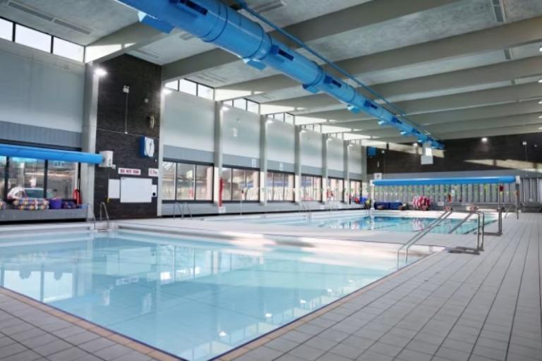 Two swimming pools, one large and one small, in a brightly lit space.