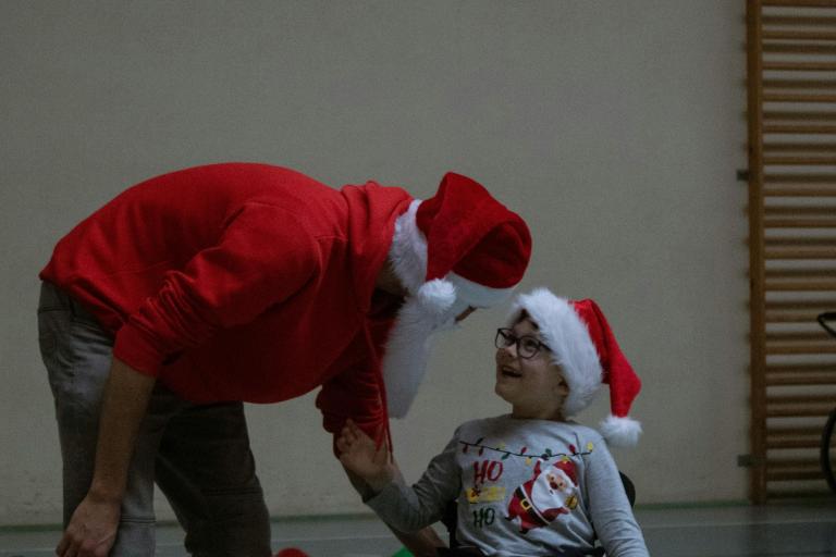 Child in wheelchair, wearing a Christmas hat