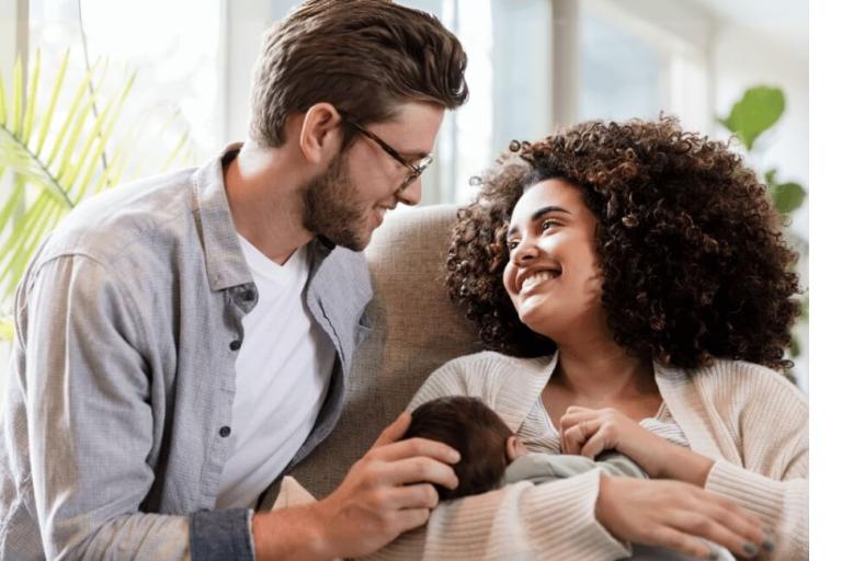 Dad looking at mum while she breastfeeds newborn baby