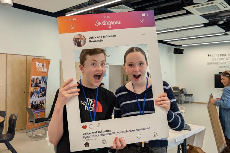 Two young people behind a selfie frame 