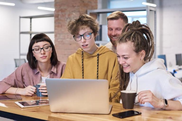 Young people gathered around laptop
