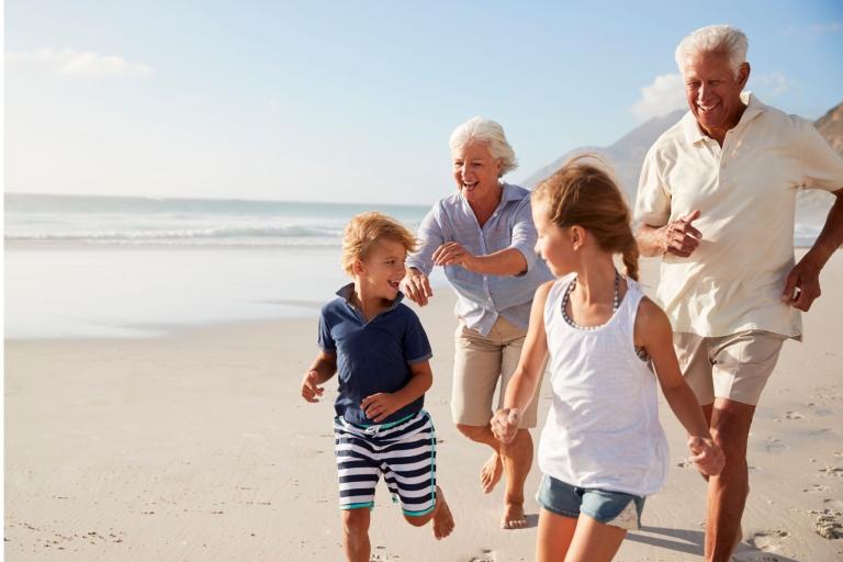 Grandparents running on the beach with grandchildren