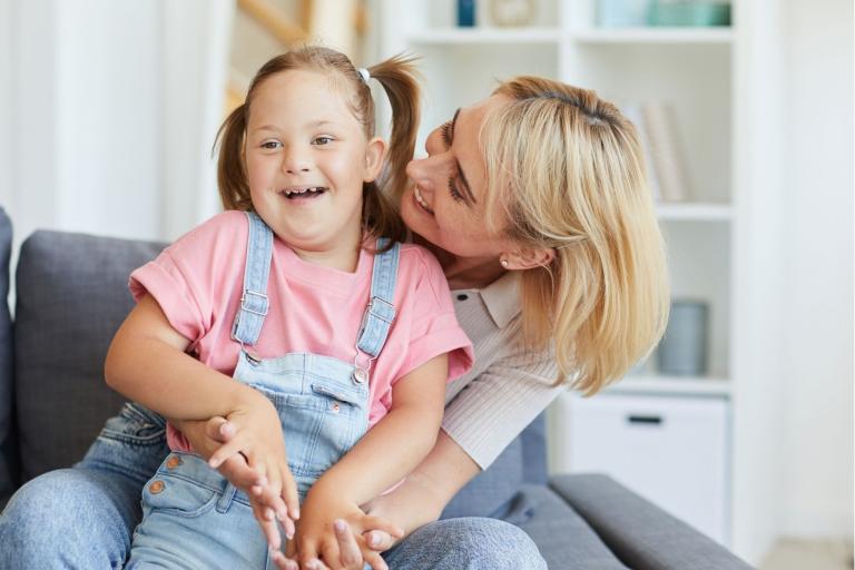 Female cuddling child with down syndrome