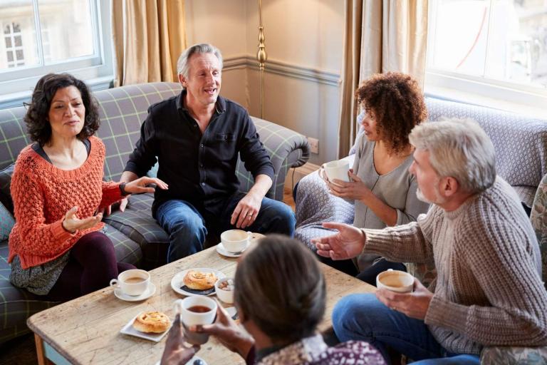 Group of adults sitting around table with refreshments