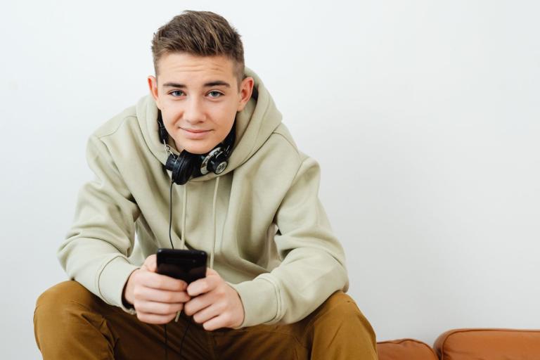 Teenager sitting on sofa holding phone