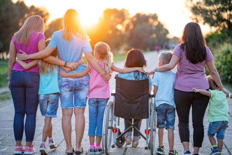 Group of people standing together arm in arm. 