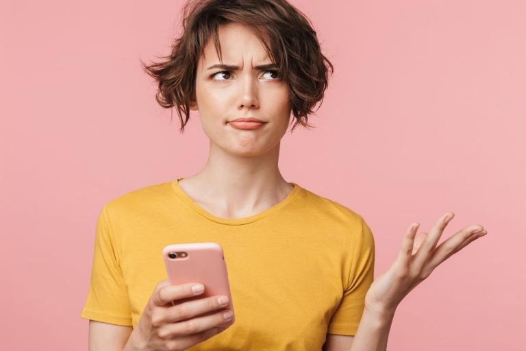 Lady holding a mobile phone looking confused