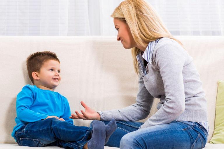 Mother sitting facing her young child on a sofa
