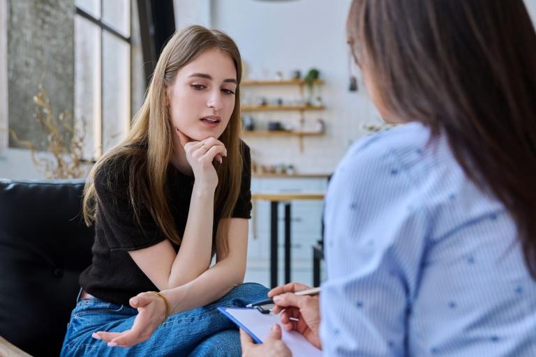 Teenager talking to person with clipboard, depicting social worker