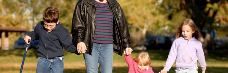 Family holding hands and walking across a small field