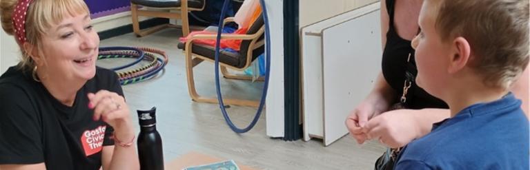 Boy talking to smiling women sat at a table