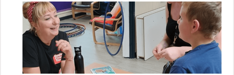 Boy talking to smiling women sat at a table